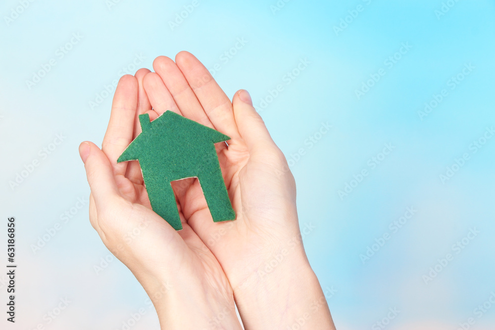 Little paper house in hand close-up, on light background Little paper house in hand close-up, on light background