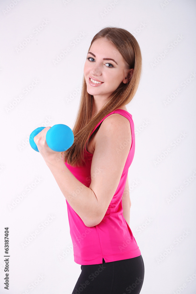 Young beautiful fitness girl exercising with dumbbells in gym Young beautiful fitness girl exercising with dumbbells in gym