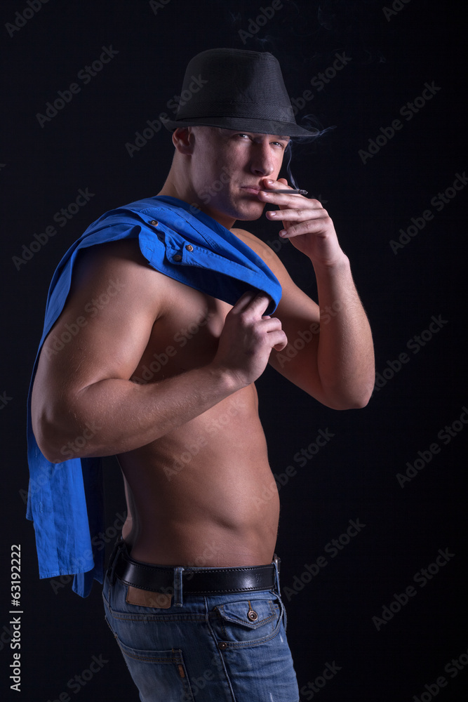 muscular young man smoking a cigarette muscular young man smoking a cigarette