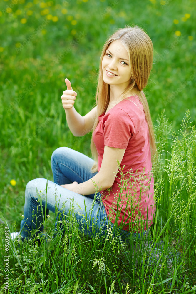 Fototapeta premium Smiling female sitting outdoors gesturing thumb up