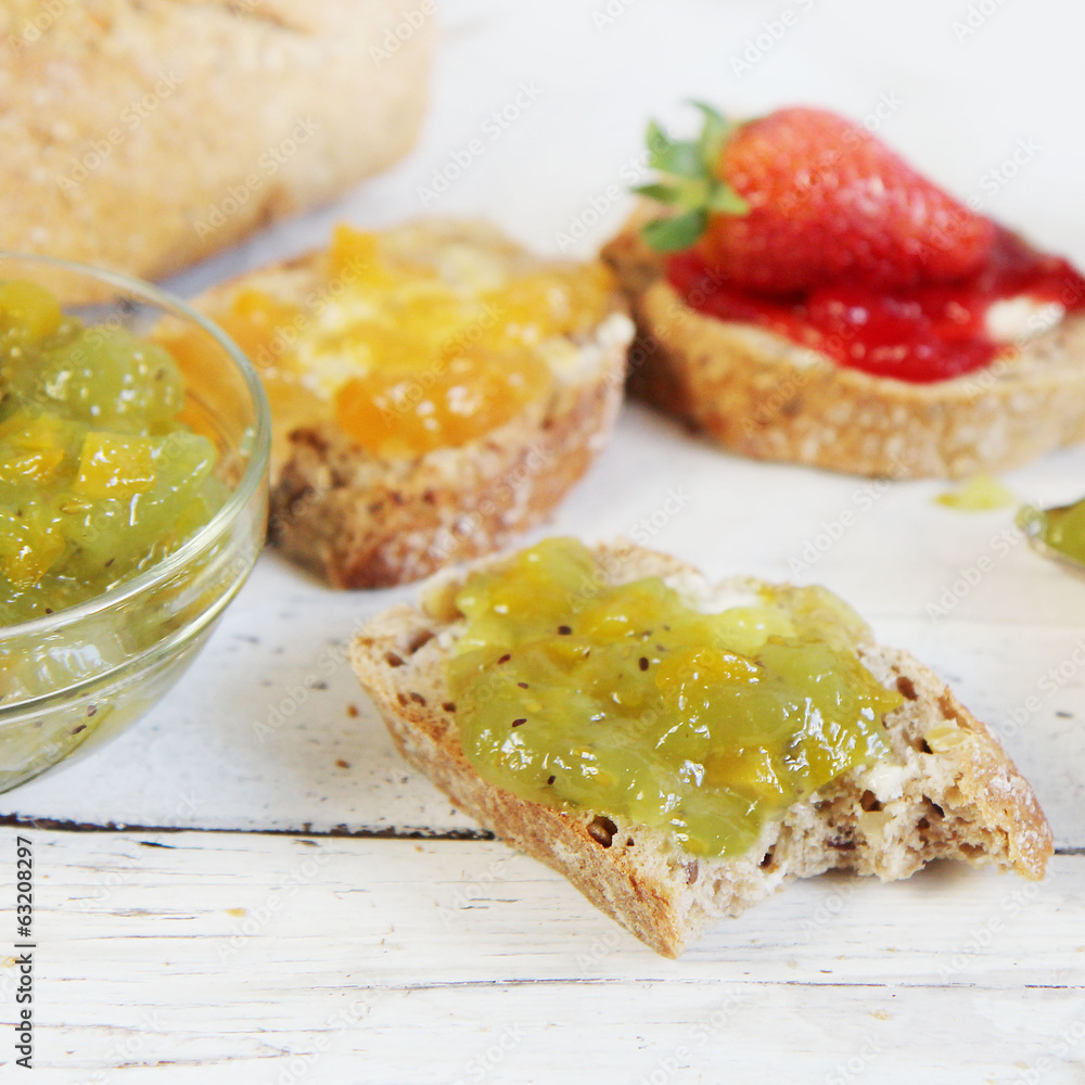 kiwi, orange and strwberry jam with slices of bread on wooden ta kiwi, orange and strwberry jam with slices of bread on wooden ta