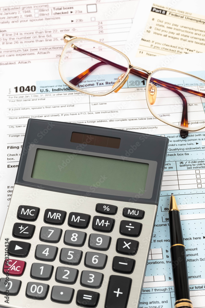 Tax form with pen, calculator, and glasses taxation concept Tax form with pen, calculator, and glasses taxation concept