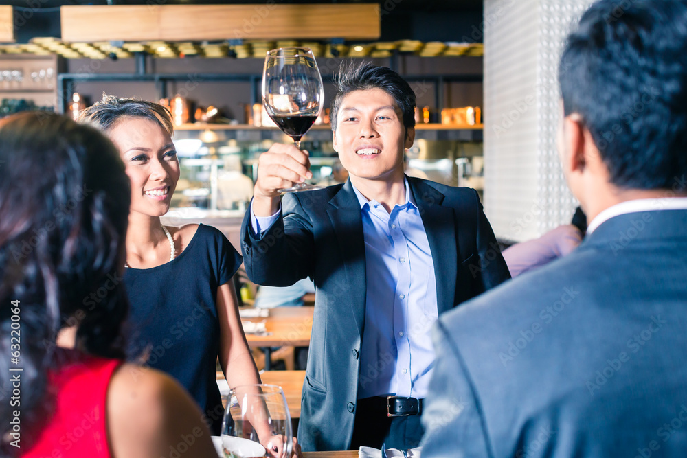 Asian friends toasting with red wine in bar
