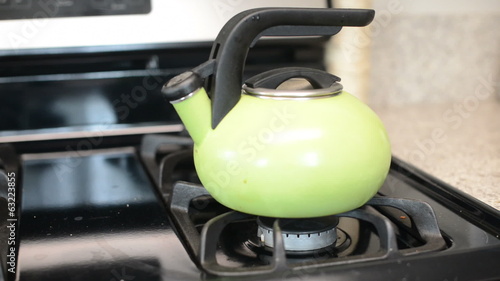 Turning off gas stove with tea kettle photo