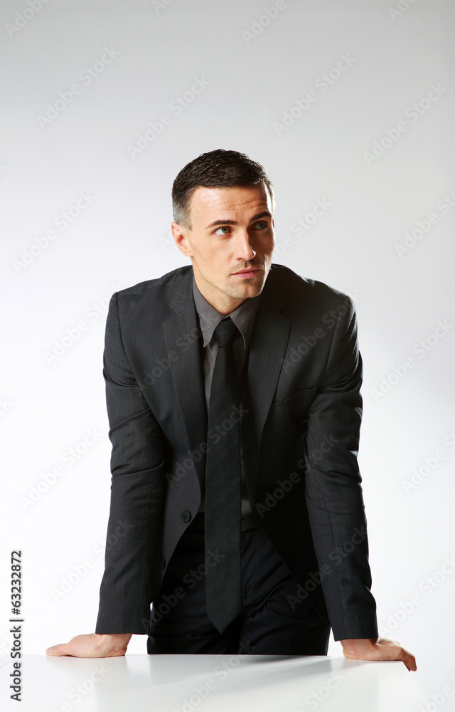 Pensive businessman standing over gray background Pensive businessman standing over gray background