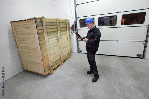 worker with tablet checking large wooden box