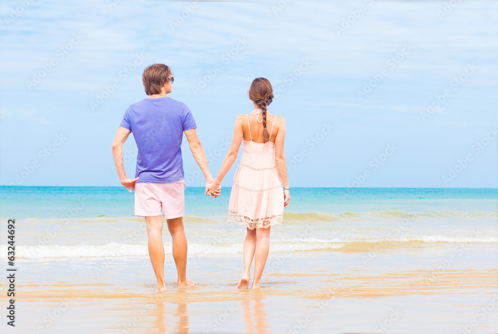 back view of couple holding hands on tropical beach
