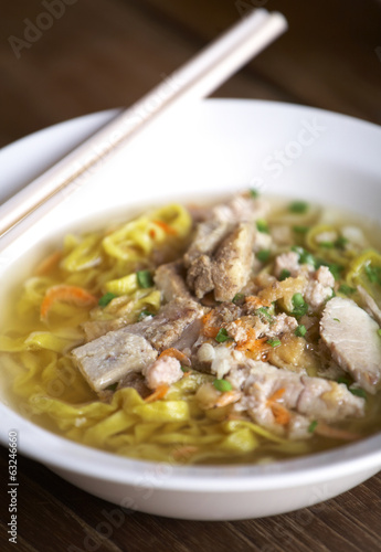 yellow thai pork noodle and pork soup on wooden table