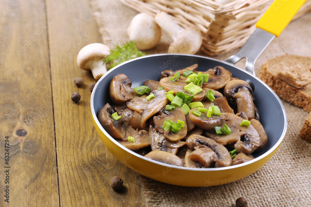 Delicious fried mushrooms in pan on table close-up Delicious fried mushrooms in pan on table close-up