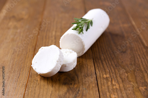 Tasty bushe cheese with rosemary, on wooden table