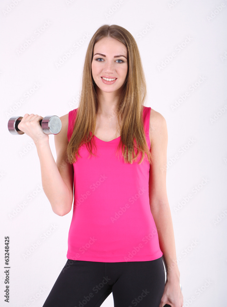 Young beautiful fitness girl exercising with dumbbells in gym Young beautiful fitness girl exercising with dumbbells in gym