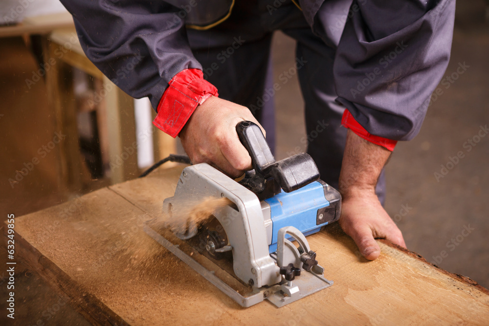 Hands carpenter working with a circular saw Hands carpenter working with a circular saw