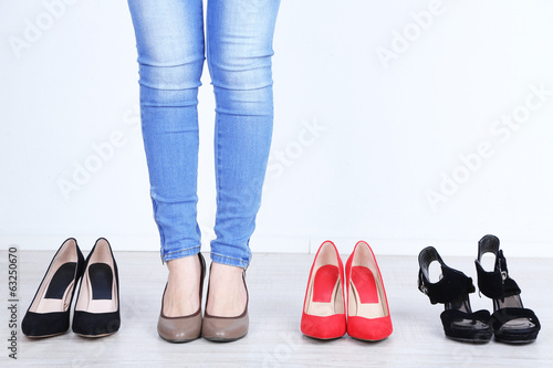 Girl chooses shoes in room on grey background