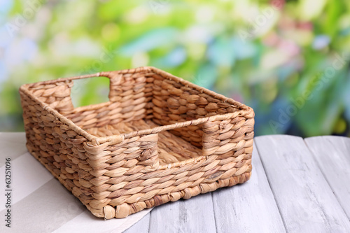 Empty wicker basket on wooden table  on bright background