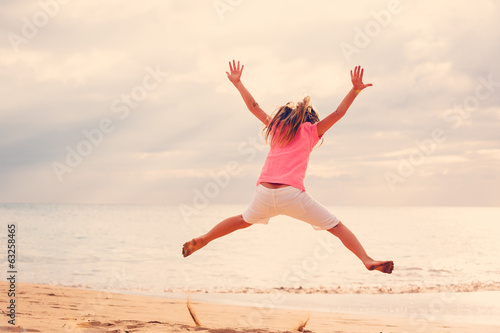 Happy Girl Jumping on the Beach at Sunset