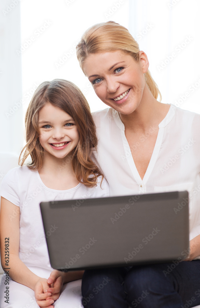 smiling mother and little girl with laptop at home