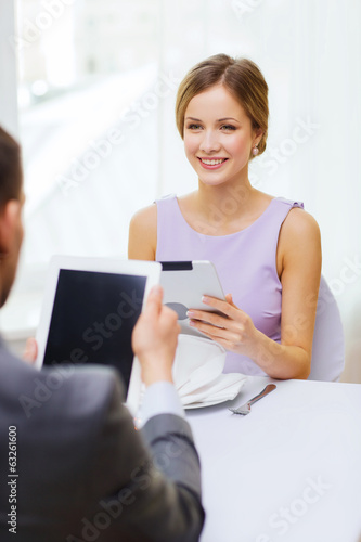 couple with menus on tablet pc at restaurant