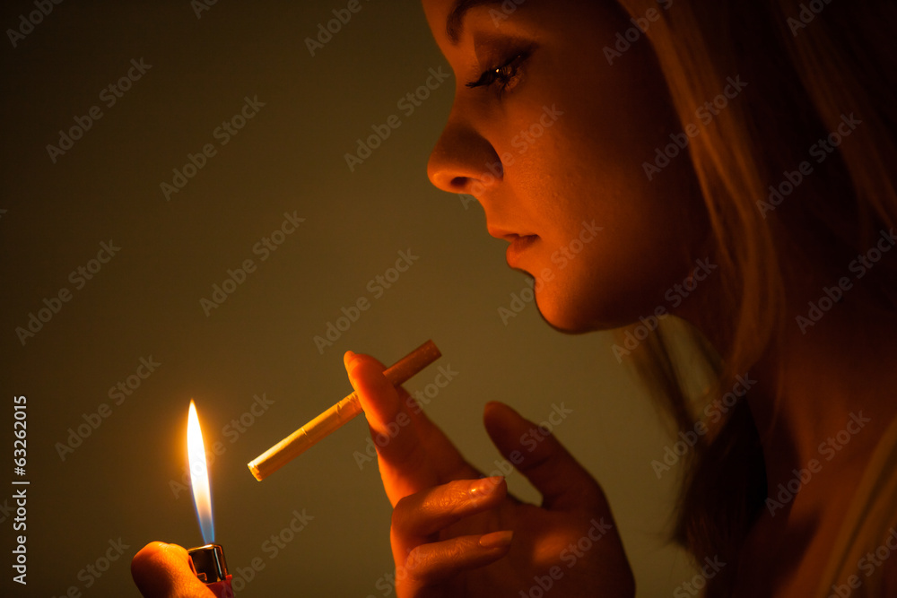 Fototapeta premium Young woman with lighter lighting up cigarette. Girl smoking.