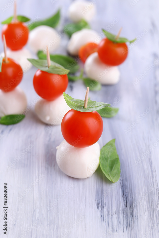 Tasty mozzarella cheese with basil and tomatoes, on wooden