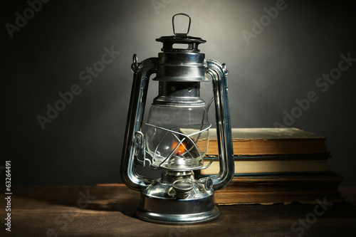 Kerosene lamp and books on dark grey background