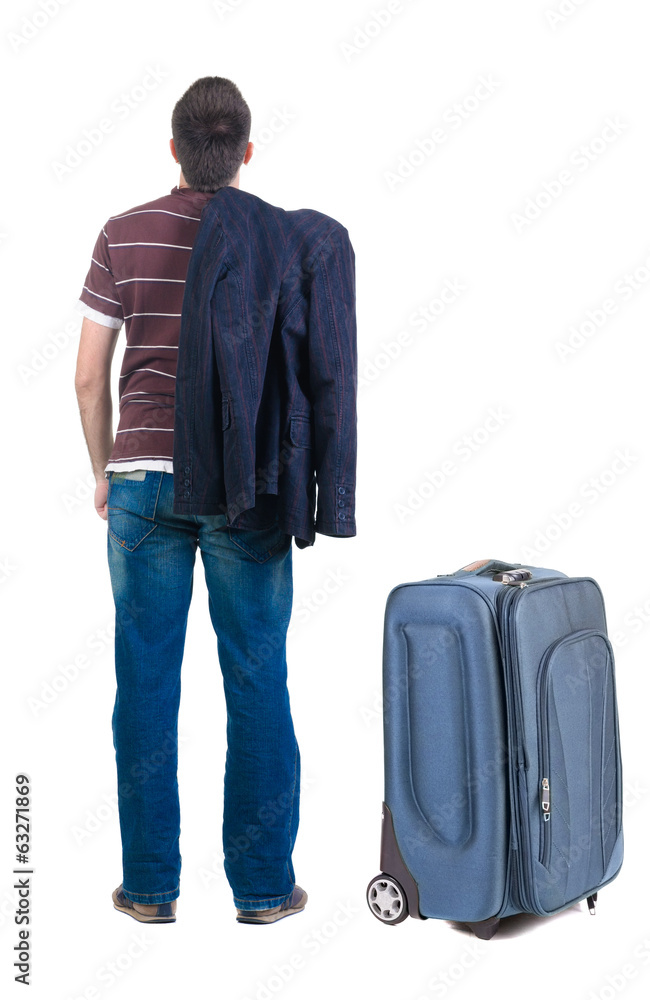 young man traveling with suitcas looks ahead. rear view. young man traveling with suitcas looks ahead. rear view.