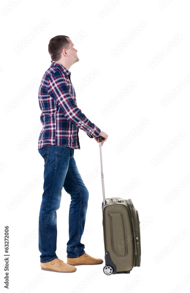 Back view of man with  green suitcase looking up.