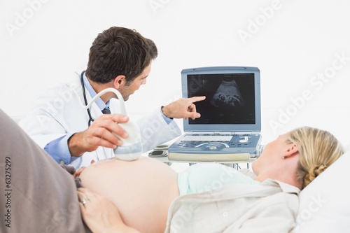 Doctor showing pregnant woman her baby on sonagram