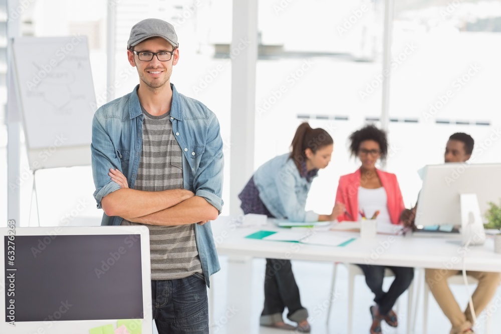 Casual male artist with colleagues in background at office Casual male artist with colleagues in background at office