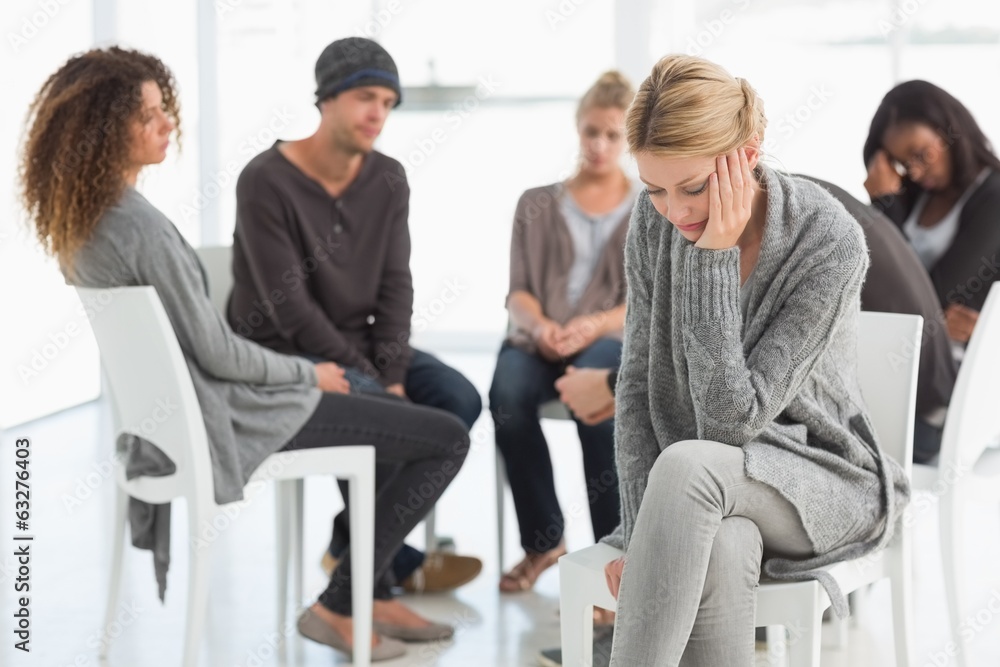 Upset woman with head in hands at rehab group Upset woman with head in hands at rehab group