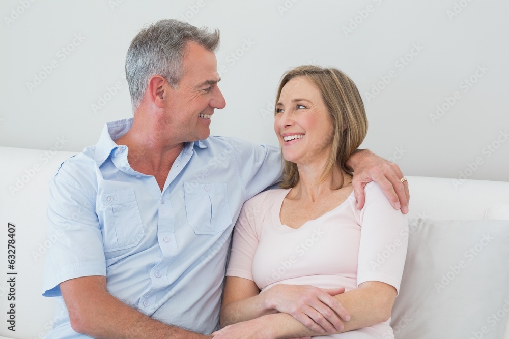 Relaxed couple sitting on sofa with arm around Relaxed couple sitting on sofa with arm around