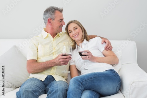 Couple with wine glasses sitting on sofa