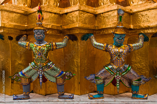 Ancient Thai sacred giants in front of the golden pagoda at the photo