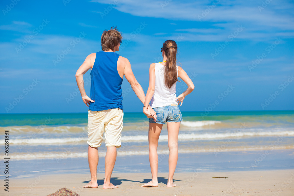 back view of couple holding hands on tropical beach