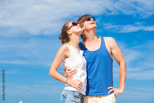 Closeup of happy young couple in sunglasses on beach smiling and