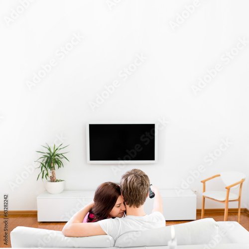Young married couple sitting on the couch and watching tv at hom