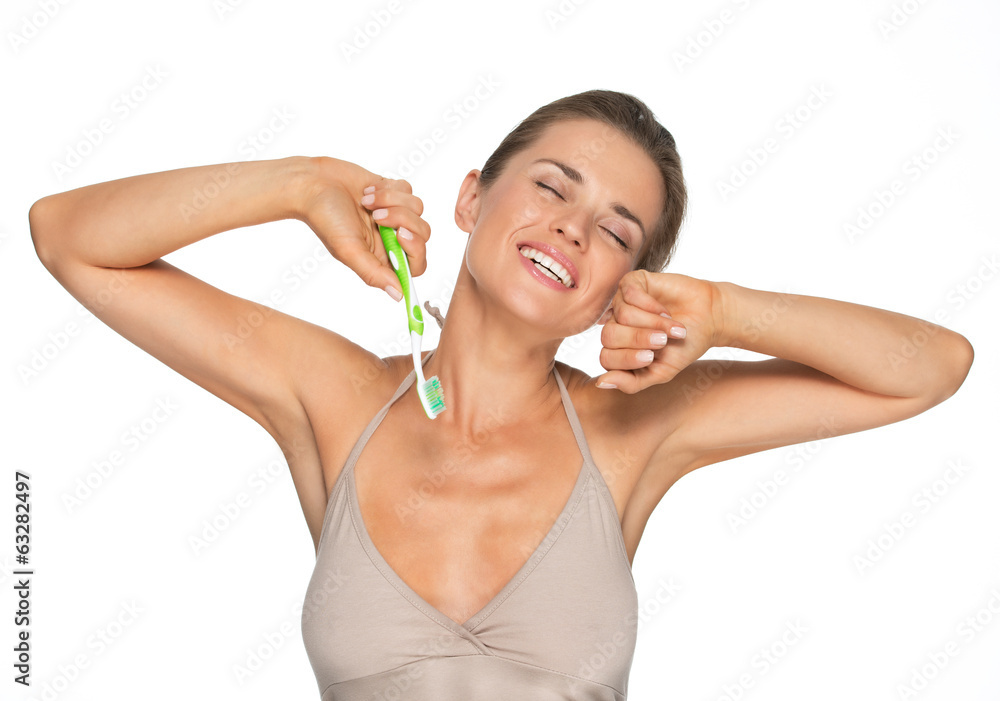 Young woman with toothbrush stretching after sleep Young woman with toothbrush stretching after sleep