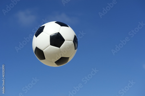 Fototapeta Naklejka Na Ścianę i Meble -  Classic Black and White Soccer Ball Football Flying in Blue Sky