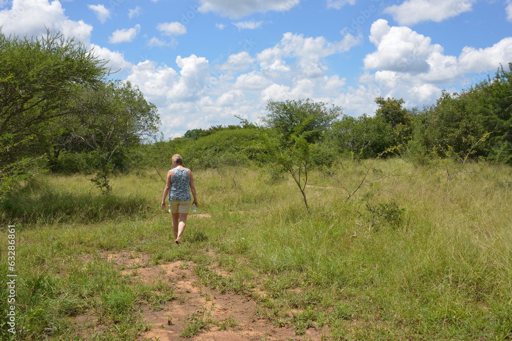 woman walking in nature with bleu sky and white clouds in africa woman walking in nature with bleu sky and white clouds in africa