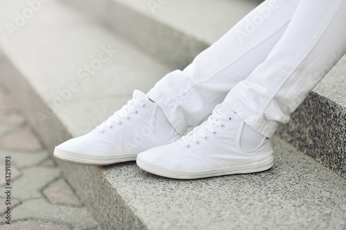 White sneakers on girl legs - closeup