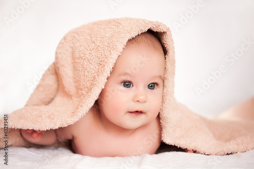 baby girl is hiding under the white blanket