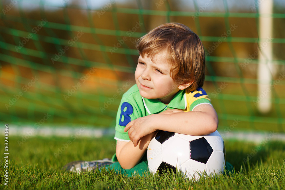 Blond boy of 4 playing soccer with football on football field Blond boy of 4 playing soccer with football on football field