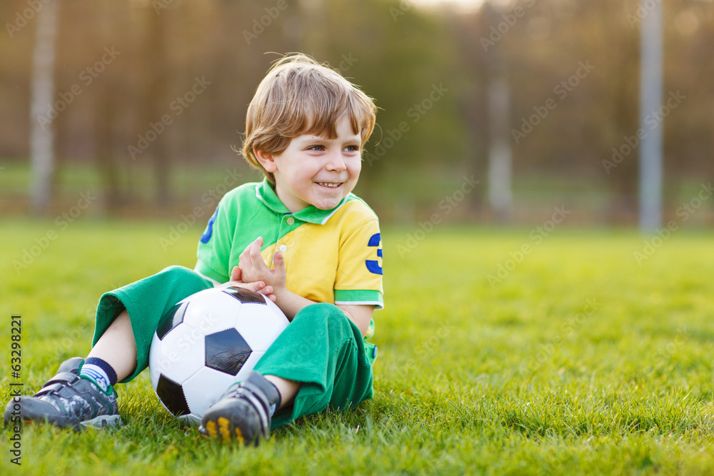 Blond boy of 4 playing soccer with football on football field Blond boy of 4 playing soccer with football on football field
