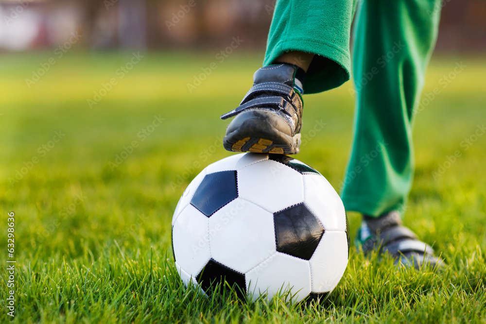 Feet of little boy with football on football field, outdoors Feet of little boy with football on football field, outdoors