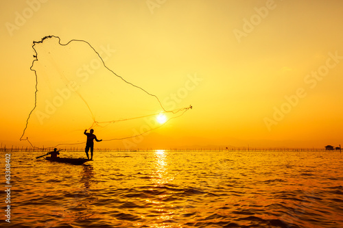 throwing fishing net during sunset , thai
