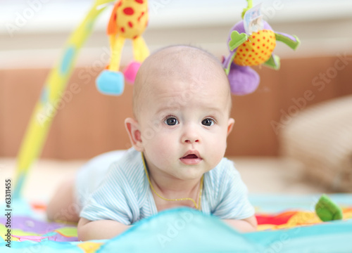 little child lying on a children's rug.