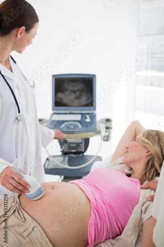 Doctor using ultrasound on pregnant woman