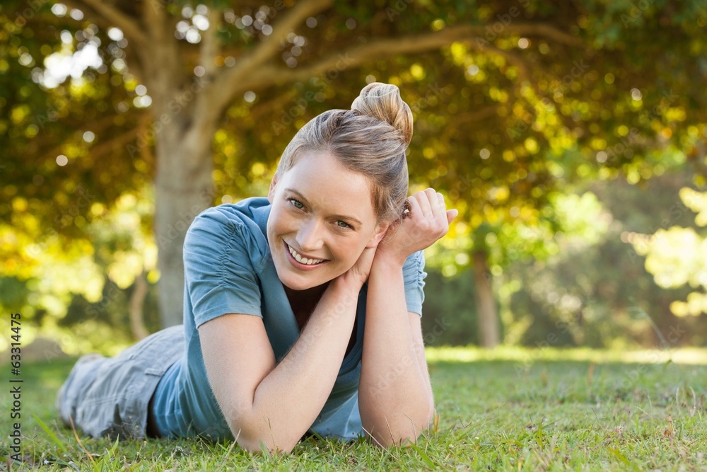 Beautiful relaxed young woman lying on grass at park Beautiful relaxed young woman lying on grass at park