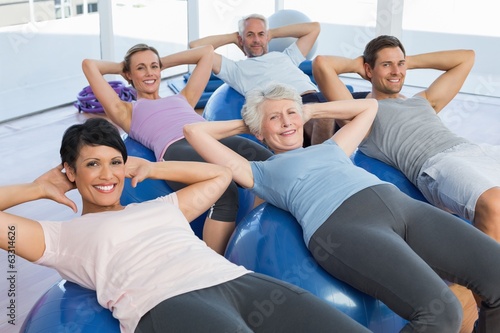 Smiling people stretching on exercise balls