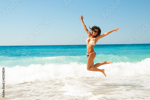Cute brunette woman jump at sea © Yarkovoy