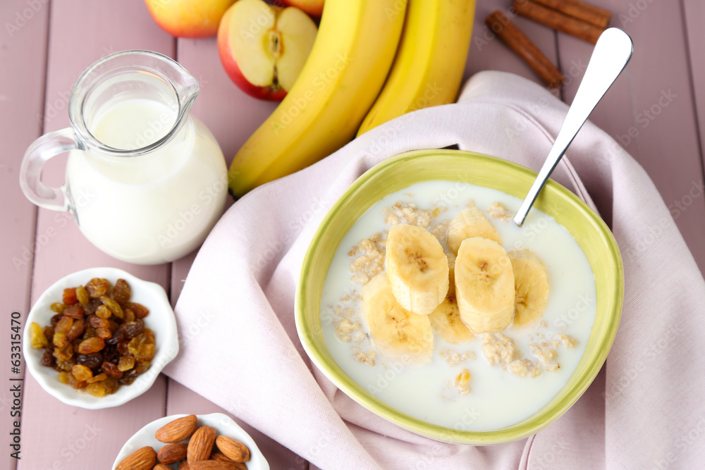 Tasty oatmeal with bananas and milk on wooden table Tasty oatmeal with bananas and milk on wooden table
